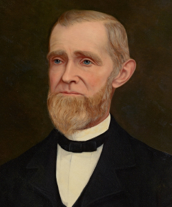 A formal portrait painting of an elderly man with a light brown beard and mustache, wearing a dark suit, white shirt, and black bow tie, set against a dark background.