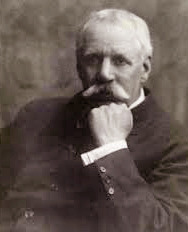 An older man with a white mustache, wearing a dark suit, rests his chin on his hand while looking to the side.